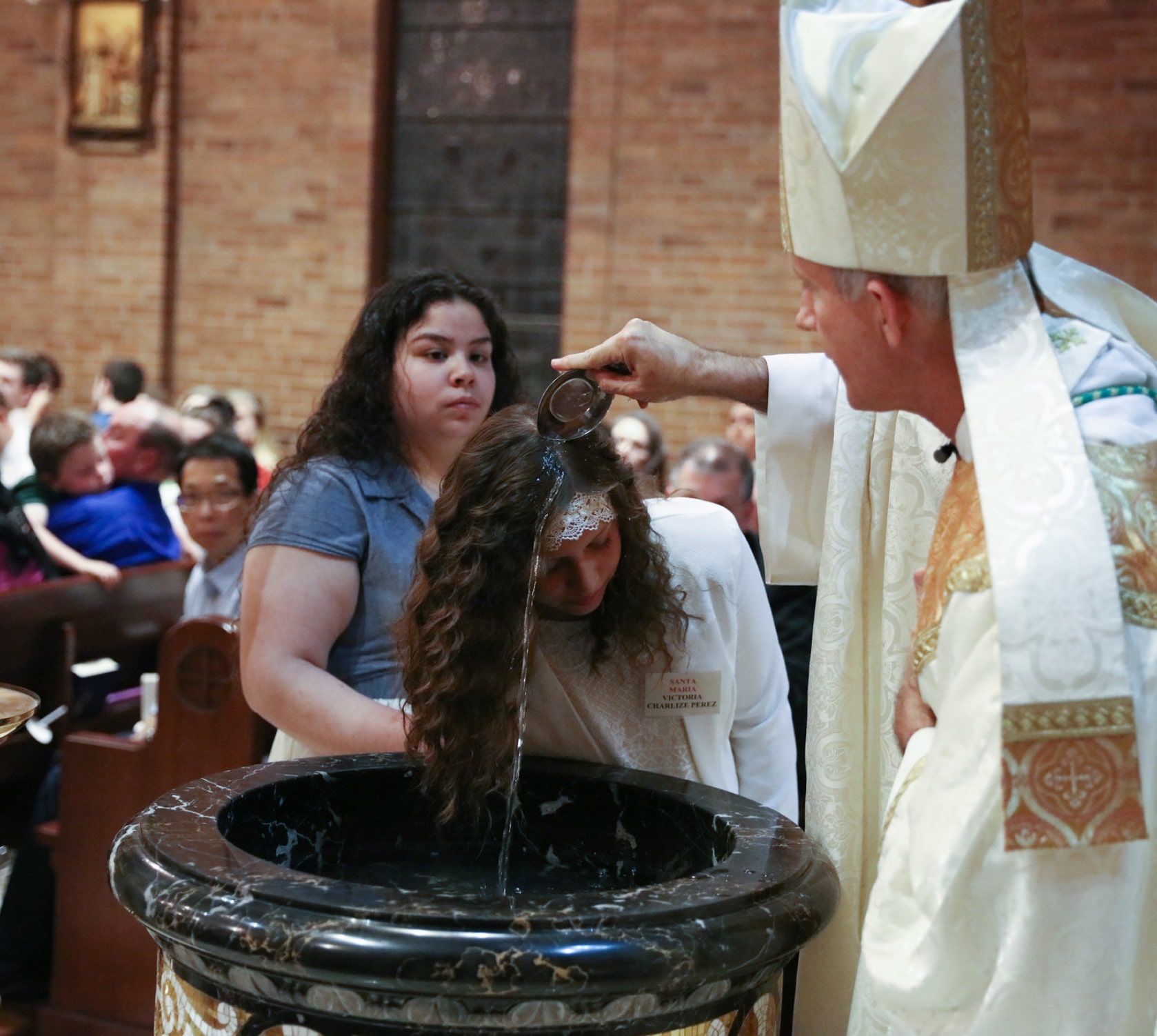 Bishop Strickland baptizing a young girl